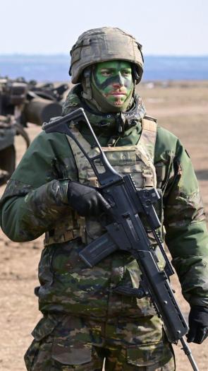 drie militairen staan in volledige uitrusting op een rij tijdens een gezamenlijke NAVO-oefening