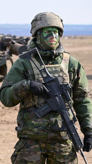 drie militairen staan in volledige uitrusting op een rij tijdens een gezamenlijke NAVO-oefening