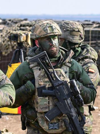 drie militairen staan in volledige uitrusting op een rij tijdens een gezamenlijke NAVO-oefening