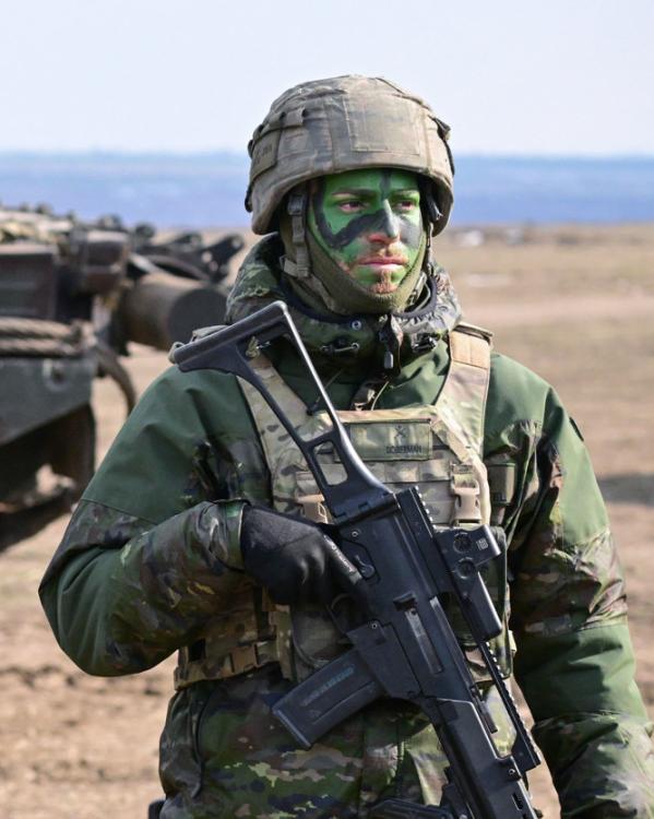 drie militairen staan in volledige uitrusting op een rij tijdens een gezamenlijke NAVO-oefening