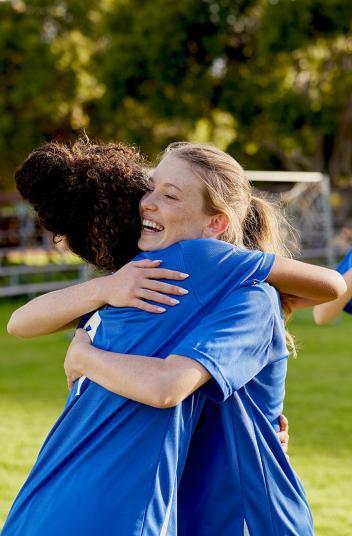 Twee voetballers die elkaar lachend de hand schudden 