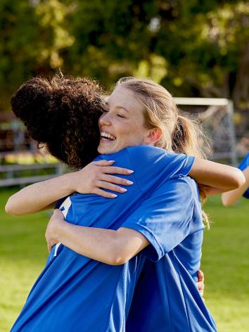 Twee voetballers die elkaar lachend de hand schudden 
