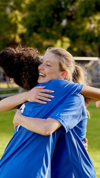 Twee voetballers die elkaar lachend de hand schudden 