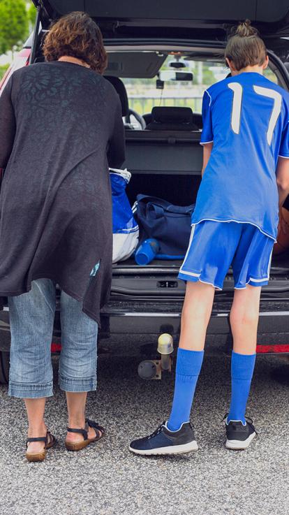Moeder helpt sport spullen uitruimen bij auto voor een wedstrijd van haar kind