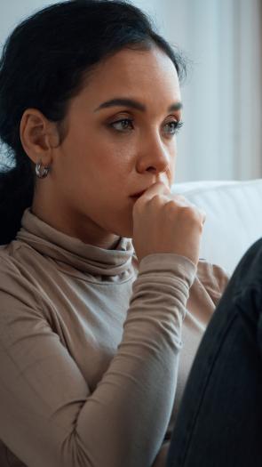 Vrouw staart emotieloos voor zich uit op de bank met hand tegen kind aan
