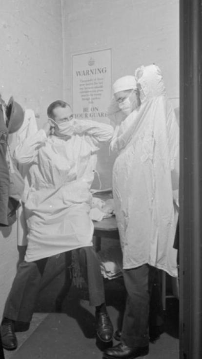 Twee legerartsen binden mondkapjes om in 1941