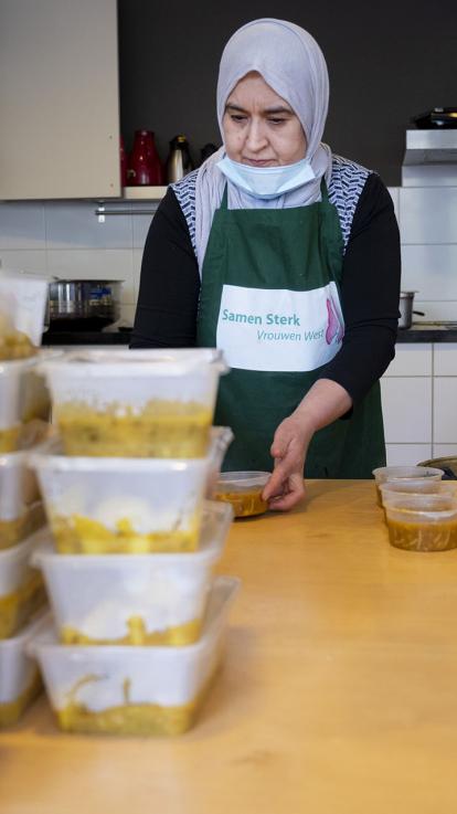 Een vrouw vult bakjes eten in de voedselbank.