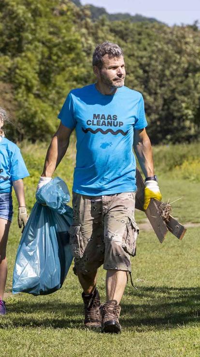 Vrijwilliger raapt afval op in de natuur.