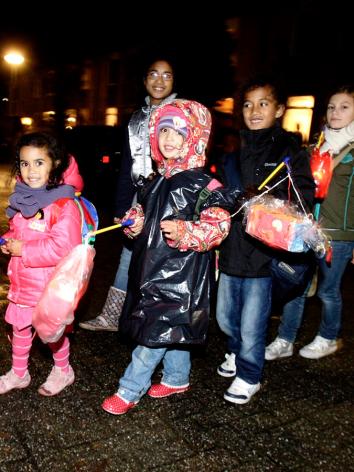 Kinderen gaan met lampions over straat 