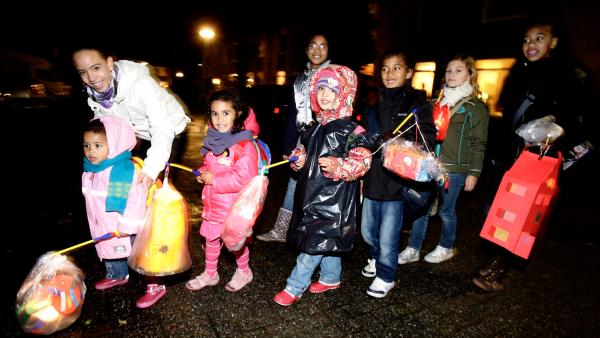 Kinderen gaan met lampions over straat 