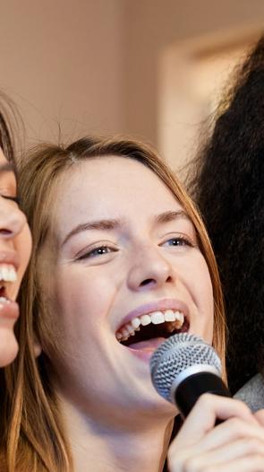 Drie vrouwen zingen samen terwijl ze een microfoon vasthouden 