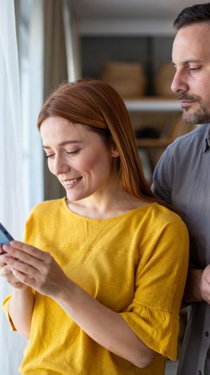 Jaloerse man kijkt stiekem mee op telefoon van partner.