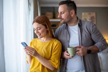 Jaloerse man kijkt stiekem mee op telefoon van partner.