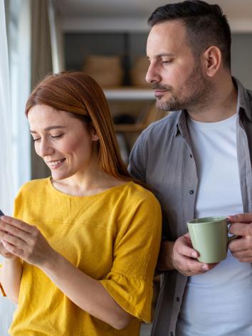 Jaloerse man kijkt stiekem mee op telefoon van partner.