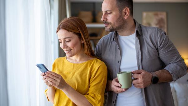 Jaloerse man kijkt stiekem mee op telefoon van partner.