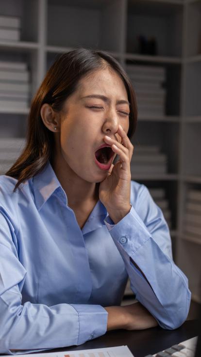 Vrouw gaapt achter laptop