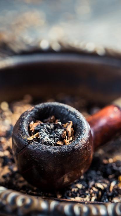 Ouderwetse pijp gevuld met gedroogde tabak in een asbak met meer tabak