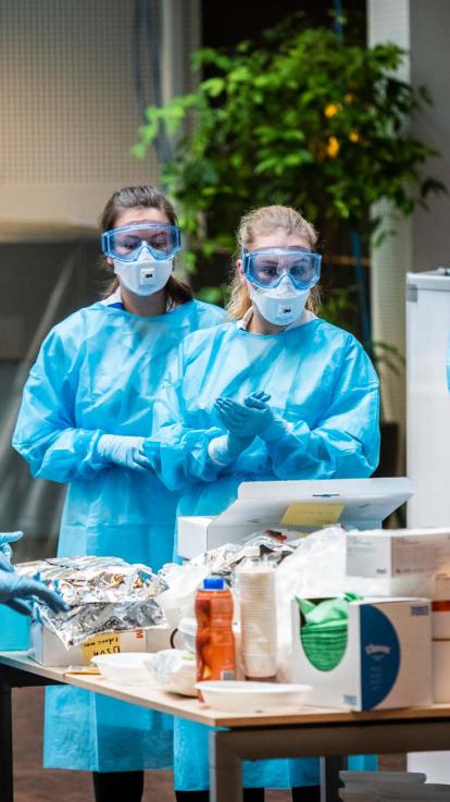 Verpleegkundigen en artsen in beschermende kleding bij een corona-polikliniek in een ziekenhuis