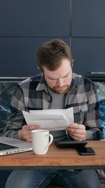 Man kijkt naar rekeningen met laptop, telefoon en rekenmachine
