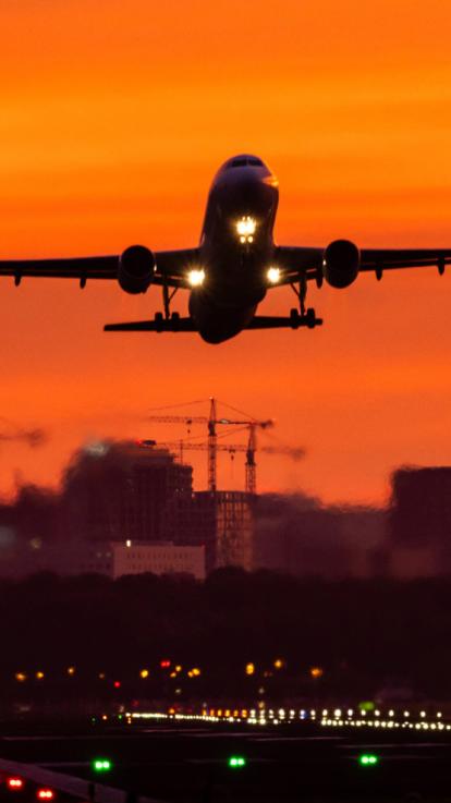 Een vliegtuig stijgt op bij zonsondergang