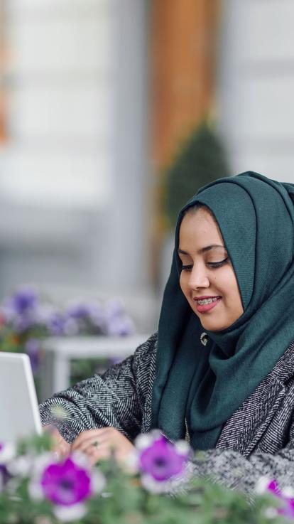 Een vrouw met een hoofddoek werkt achter haar laptop