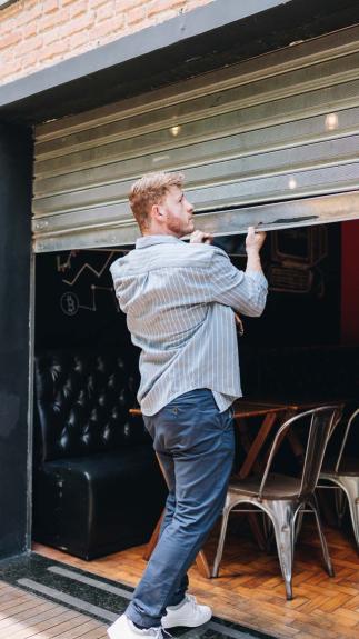 een man doet de roldeur van zijn horecazaak dicht
