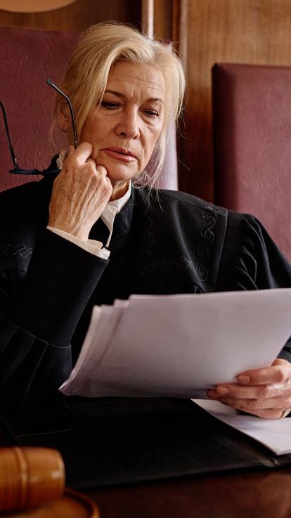 Een rechter kijkt serieus naar documenten in haar hand