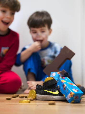 Kindjes kijken blij naar schoen met cadeautjes en een chocoladeletter