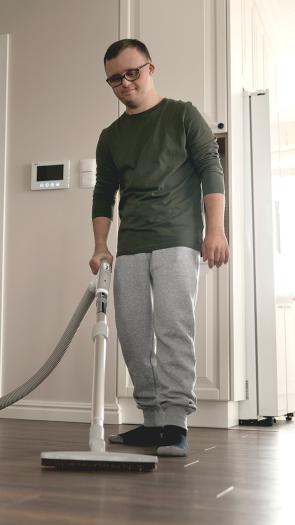Een man stofzuigt de woonkamer