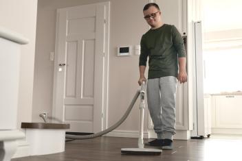 Een man stofzuigt de woonkamer