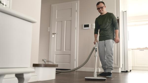 Een man stofzuigt de woonkamer