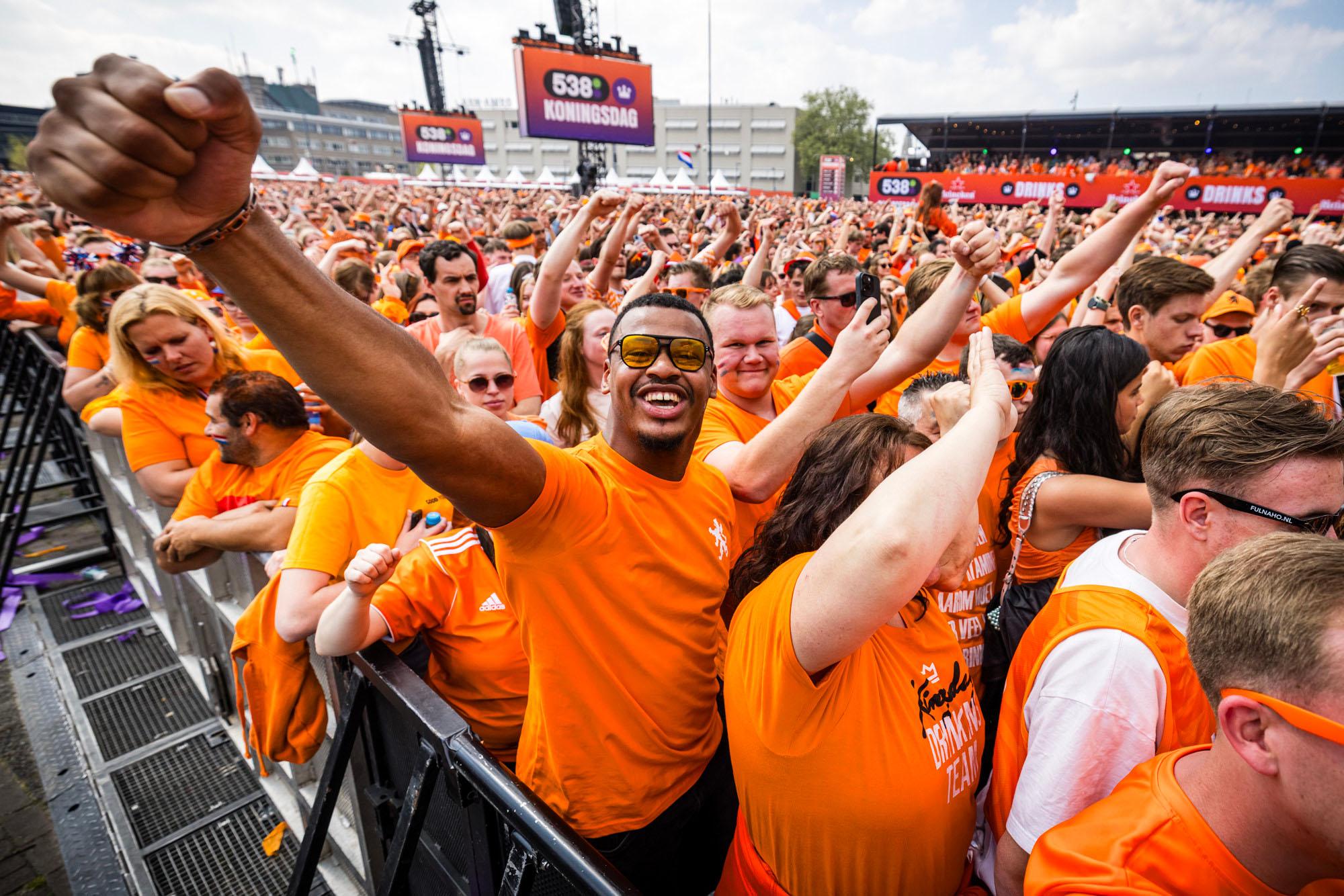 Feestende en vrolijke koningsdagvierders in het oranje gekleed tijdens een koningsdagconcert