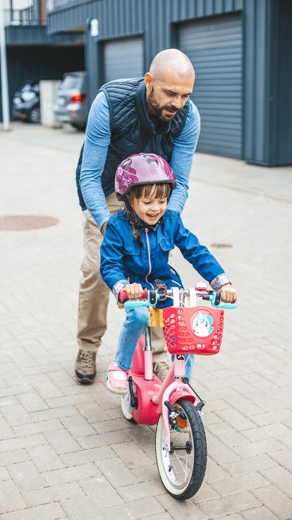 Dochter leert fietsen met vader die haar duwt