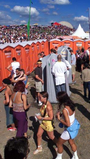 Mensen staan bij de toiletten te wachten op een festivalterrein 