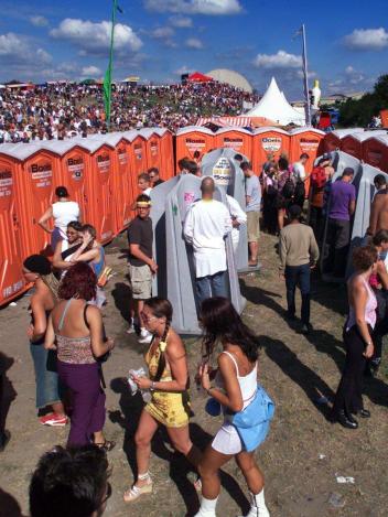 Mensen staan bij de toiletten te wachten op een festivalterrein 
