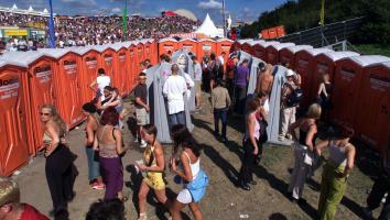Mensen staan bij de toiletten te wachten op een festivalterrein 