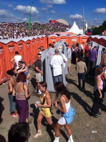 Mensen staan bij de toiletten te wachten op een festivalterrein 