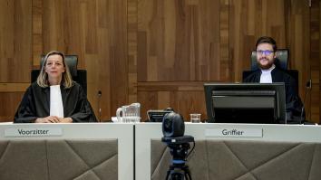 Rechter en griffier zitten in de rechtbank achter tafel. Griffier zit achter computerscherm