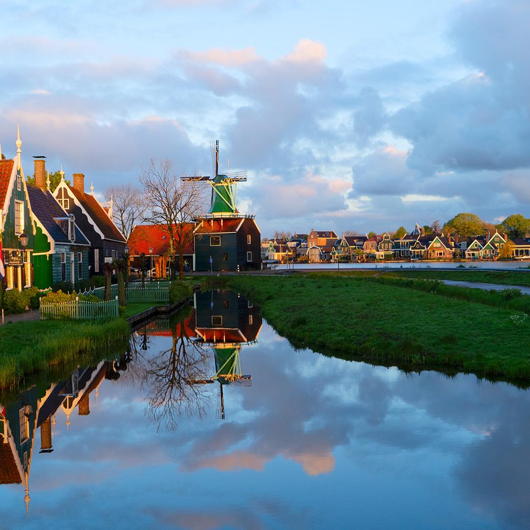 Een Nederlands polderlandschap met een molen, water en gekleurde huizen