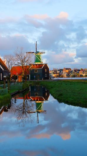 Een Nederlands polderlandschap met een molen, water en gekleurde huizen
