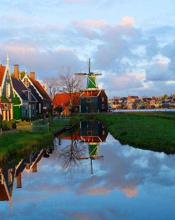 Een Nederlands polderlandschap met een molen, water en gekleurde huizen