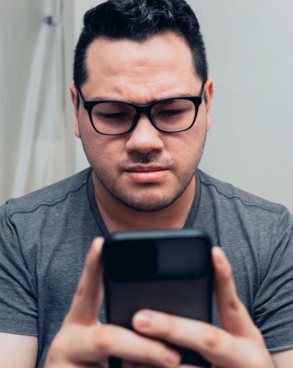 Een man kijkt verontrust naar zijn telefoon