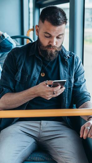 Iemand kijkt op zijn mobiele telefoon in de bus