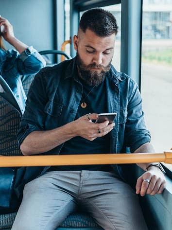 Iemand kijkt op zijn mobiele telefoon in de bus
