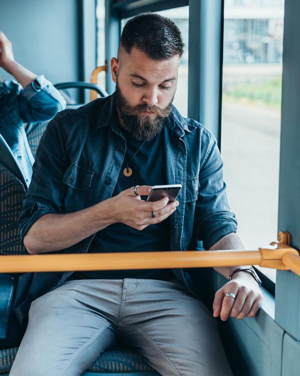 Iemand kijkt op zijn mobiele telefoon in de bus