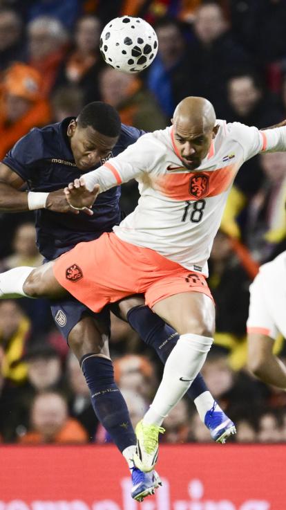 Twee voetballers doen een kopduel. Een voetballer draagt het uitshirt van het Nederlands elftal en de ander het thuisshirt van Ecuador.