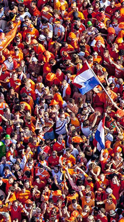 Bovenaanzicht van mensen op straat gekleed in het oranje met Nederlandse vlaggen.