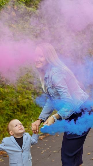 Jong gezin blaast roze en blauwe rook als genderreveal in de lucht