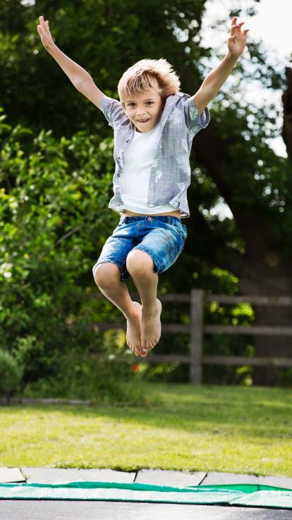 Een jongen springt op een trampoline in de zomer