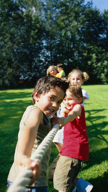 Een groep kinderen aan het touwtjetrekken op een grasveld